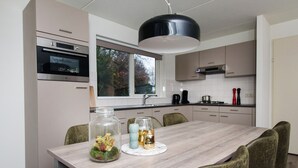 A modern kitchen with a dining table, chairs, and a window. - Modern Villa Near Veluwe (Hoenderloo)