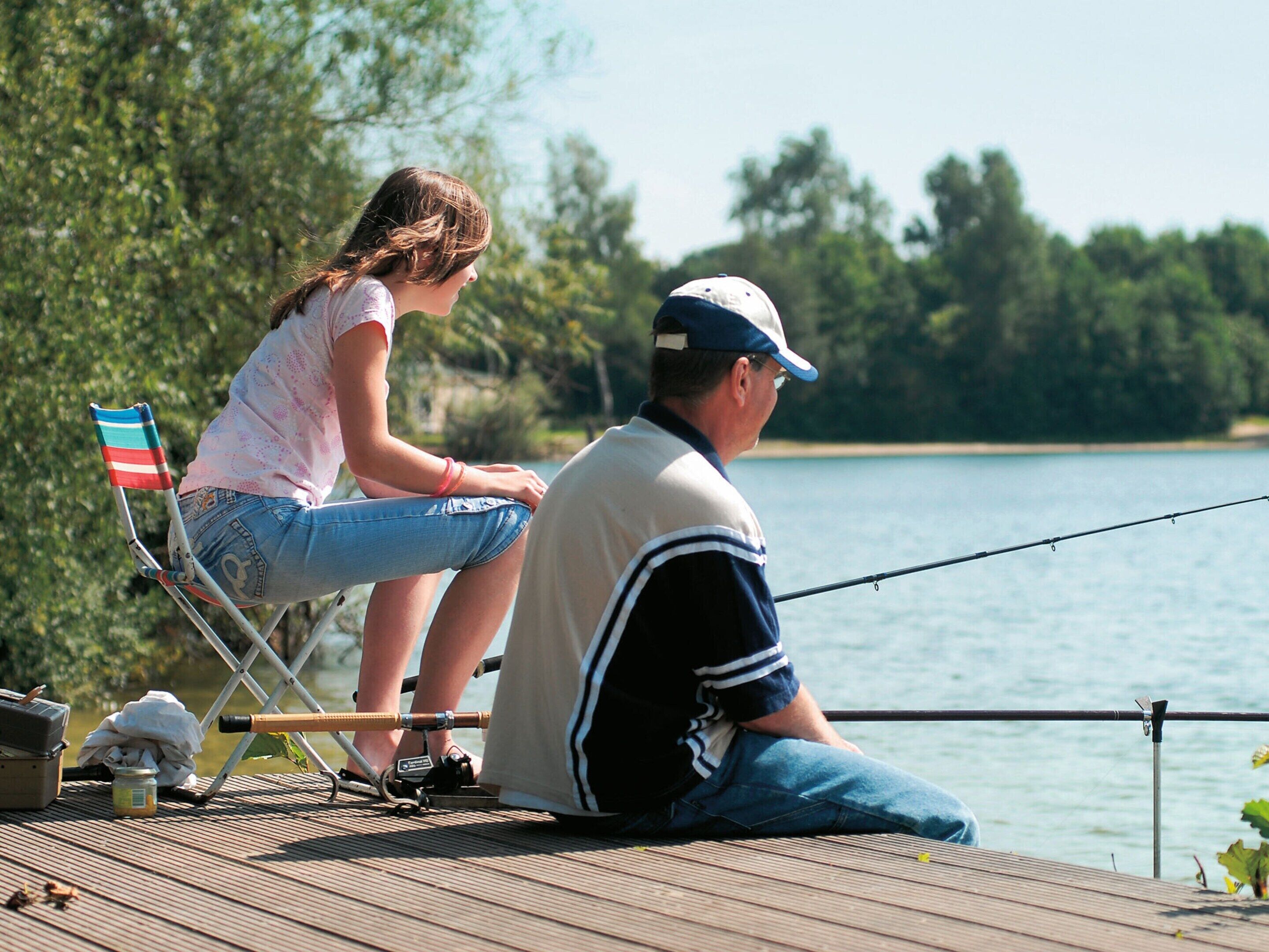 A wooden deck with a fishing rod, a chair, and a flag.