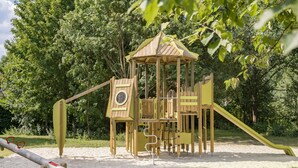 A playground with a wooden climbing structure, a slide, and a seesaw. - Chic Chalet Near Almelo (Hoge Hexel)