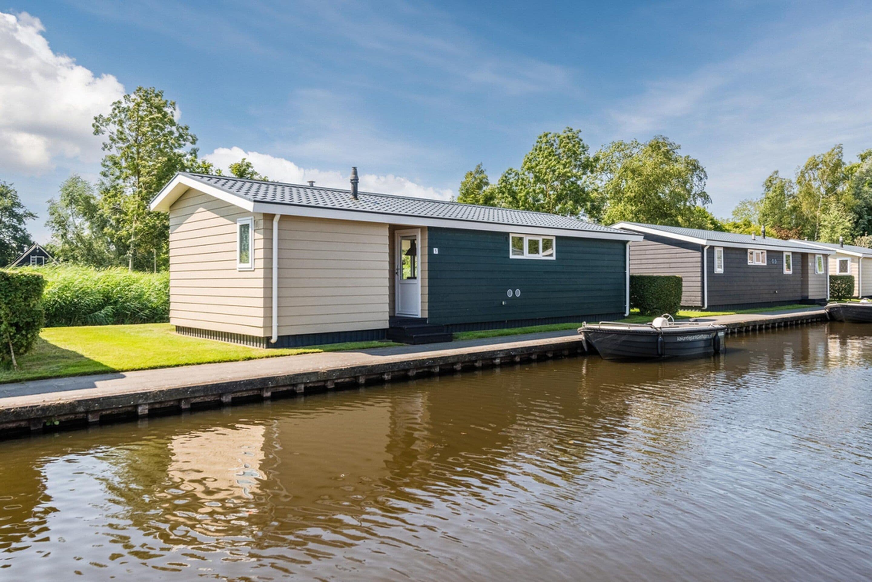 A row of mobile homes by a canal with a grassy area in front.