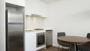 Una cocina moderna con armarios blancos, electrodomésticos de acero inoxidable y una mesa de comedor redonda.