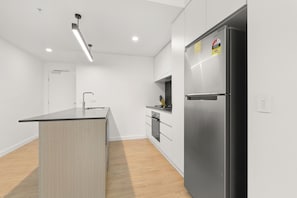 Una cocina moderna con una isla central, electrodomésticos de acero inoxidable y suelo de madera clara.