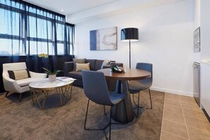 Un salon moderne avec un canapé, des fauteuils, une table basse et une lampe.