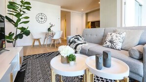 Un salon moderne avec un canapé gris, une table basse blanche et un coin repas comprenant une table et des chaises blanches.