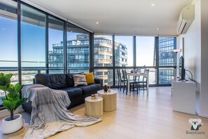 Un salon moderne doté d’une grande fenêtre, d’un canapé, d’une table basse et d’un coin repas.