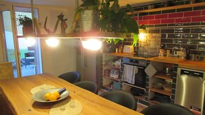 Una cocina con una mesa de madera, sillas, una planta en maceta y varios electrodomésticos.