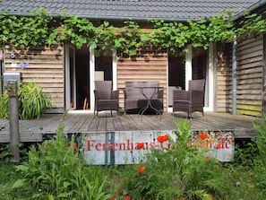 A wooden house with a covered porch, wicker furniture, and a sign with red lettering.