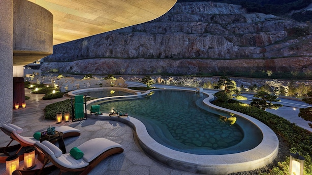 Área da piscina com espreguiçadeiras e vista para o céu noturno.