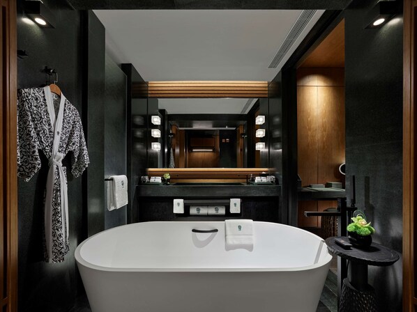 Un baño moderno con una bañera independiente, un tocador de madera y un espejo grande.