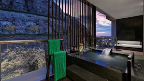 Uma área de spa moderna com vista para terreno rochoso e um pôr do sol.