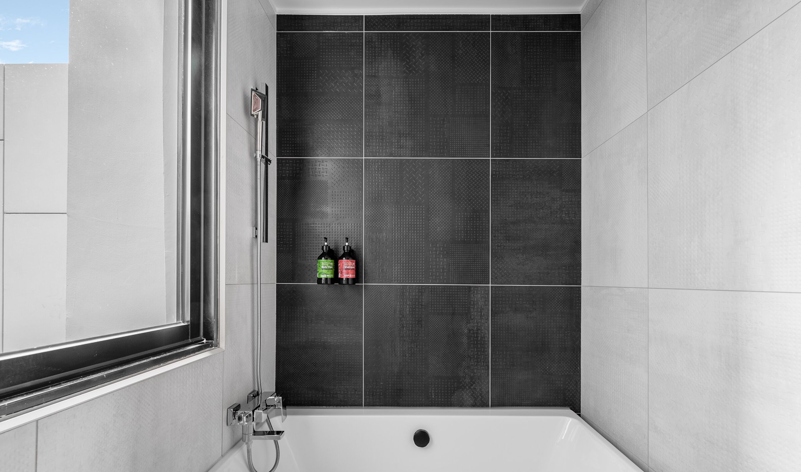 A modern bathroom with a shower and a bathtub, featuring a large window and a tiled wall.