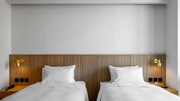 A double room with two beds, wooden headboard, bedside tables, and wall-mounted light fixtures.
