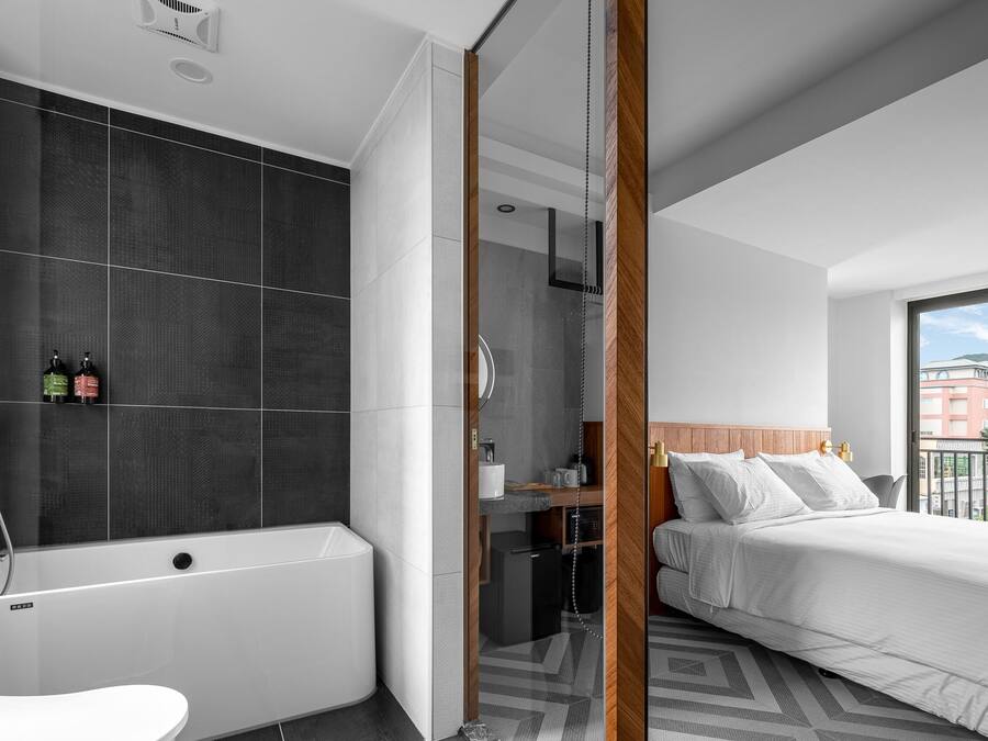 Habitación de hotel moderna con bañera, cama y vistas a la ciudad.