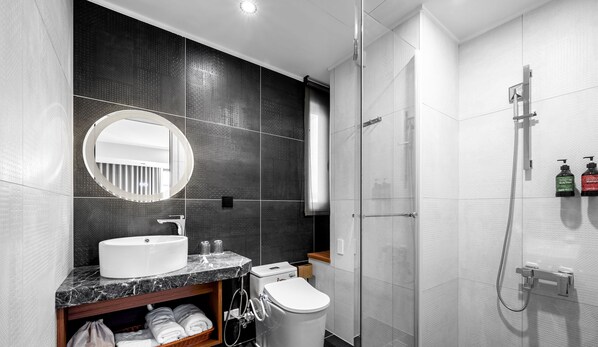 Un baño moderno con lavabo de mármol, inodoro, ducha y espejo.