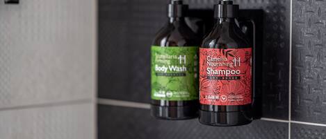 Two bottles of body wash and shampoo on a tiled wall.