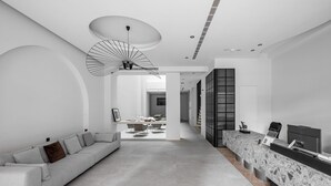 A modern interior with a minimalist design, featuring a sofa, a reception desk, and a unique ceiling light fixture. - Black Horn B&B (Hengchun)