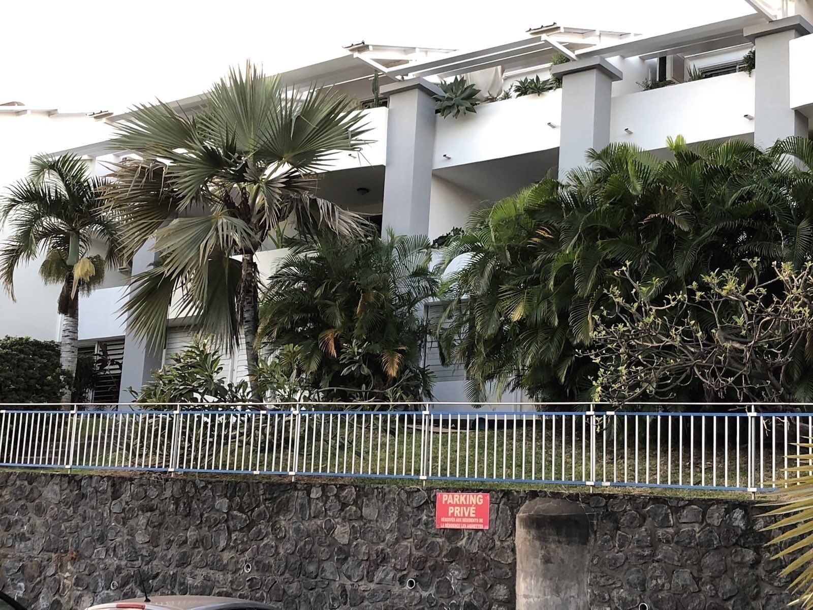 A modern building with a stone wall and a white fence.