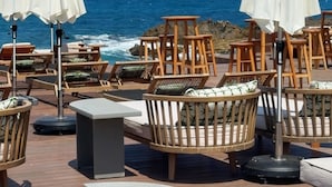 A seaside patio with wooden chairs and tables, white umbrellas, and a view of the ocean. - Bebatroun Beach Hotel (Batroun)