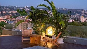 A rooftop terrace with a pool, lounge chairs, and a view of the cityscape.