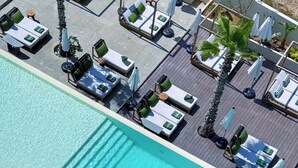 A rooftop pool with sun loungers and umbrellas, surrounded by palm trees. - Bebatroun Beach Hotel (Batroun)