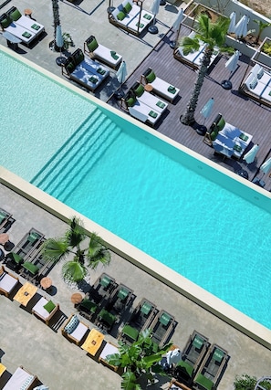 A rooftop pool with sun loungers and umbrellas, surrounded by palm trees. - Bebatroun Beach Hotel (Batroun)