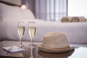 Deux verres de vin blanc sur une table, accompagnés d’un chapeau de paille et d’un carnet.