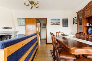 A dining area with a wooden table and chairs, a blue cushioned bench, and a chandelier.