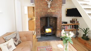 A cozy living room with a brick fireplace, a sofa, a coffee table, and a bookshelf.
