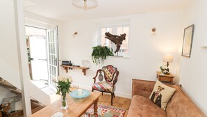 A living room with a wooden coffee table, a patterned rug, a brown sofa, a chair, and a window with a decorative item.