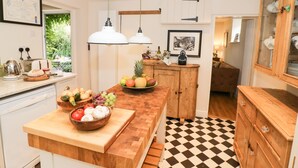 A modern kitchen with a wooden island, white cabinetry, and a checkered floor.