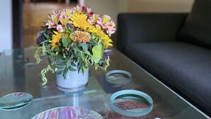 A living room with a glass coffee table, a vase of flowers, and a couch. - House (Lohmar)