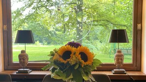 A dining table with a vase of sunflowers and two Buddha statues on either side. - House (Lohmar)