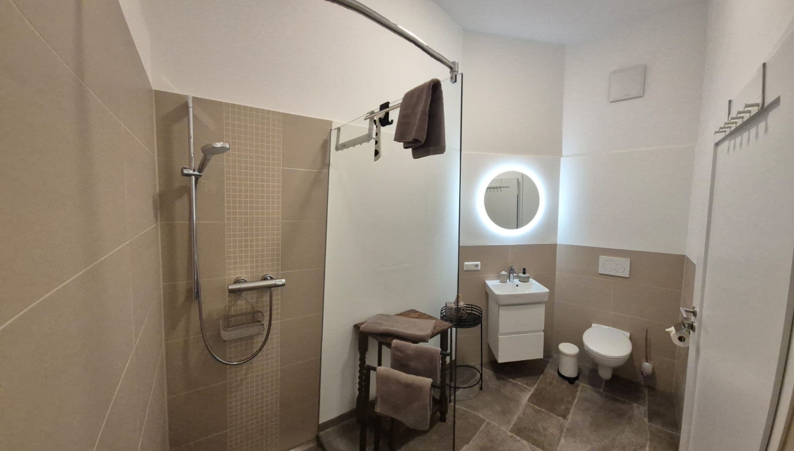 A bathroom with a shower, a sink, a toilet, and a towel rack.