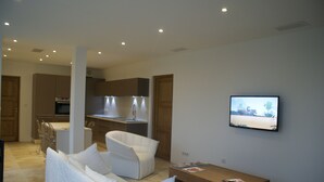 A modern living room with a white sofa, a wooden coffee table, and a television mounted on the wall. - Facing the sea, 30 m from the beach, luxury villa, air-conditioned  (Serra-di-Ferro)
