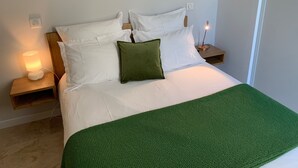 A neatly made bed with white linens and a green throw blanket, a bedside lamp, and a nightstand with a lamp. - Facing the sea, 30 m from the beach, luxury villa, air-conditioned  (Serra-di-Ferro)