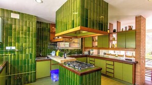 Een keuken met groene tegels, een centraal kookeiland en houten kastjes.