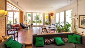 Een ruime woonkamer met een bank, stoelen, een eettafel en een keukenhoek.