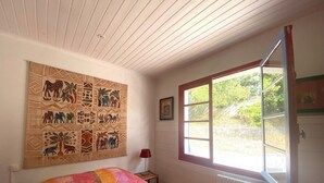 Une chambre à coucher avec un lit, une grande tapisserie, une fenêtre et un radiateur.