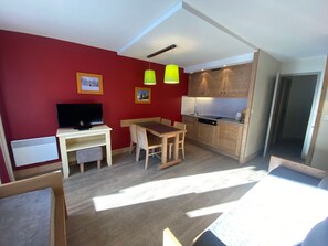 A compact living space with a dining area, kitchenette, and a television.