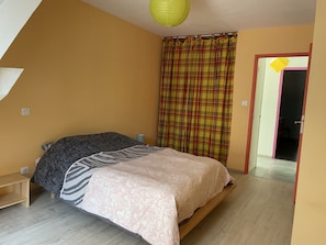 A bedroom with a bed, a wooden nightstand, a yellow hanging light, and a plaid curtain. - Large apartment in the heart of La Côte Saint André (La Côte-Saint-André)