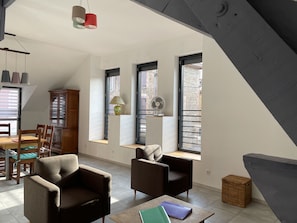 A modern loft apartment with a dining area, two sofas, a small table, and large windows. - Large apartment in the heart of La Côte Saint André (La Côte-Saint-André)