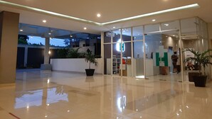 A modern lobby with glass doors, potted plants, and a clean, reflective floor.