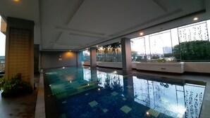 An indoor swimming pool with a tiled floor and large windows.