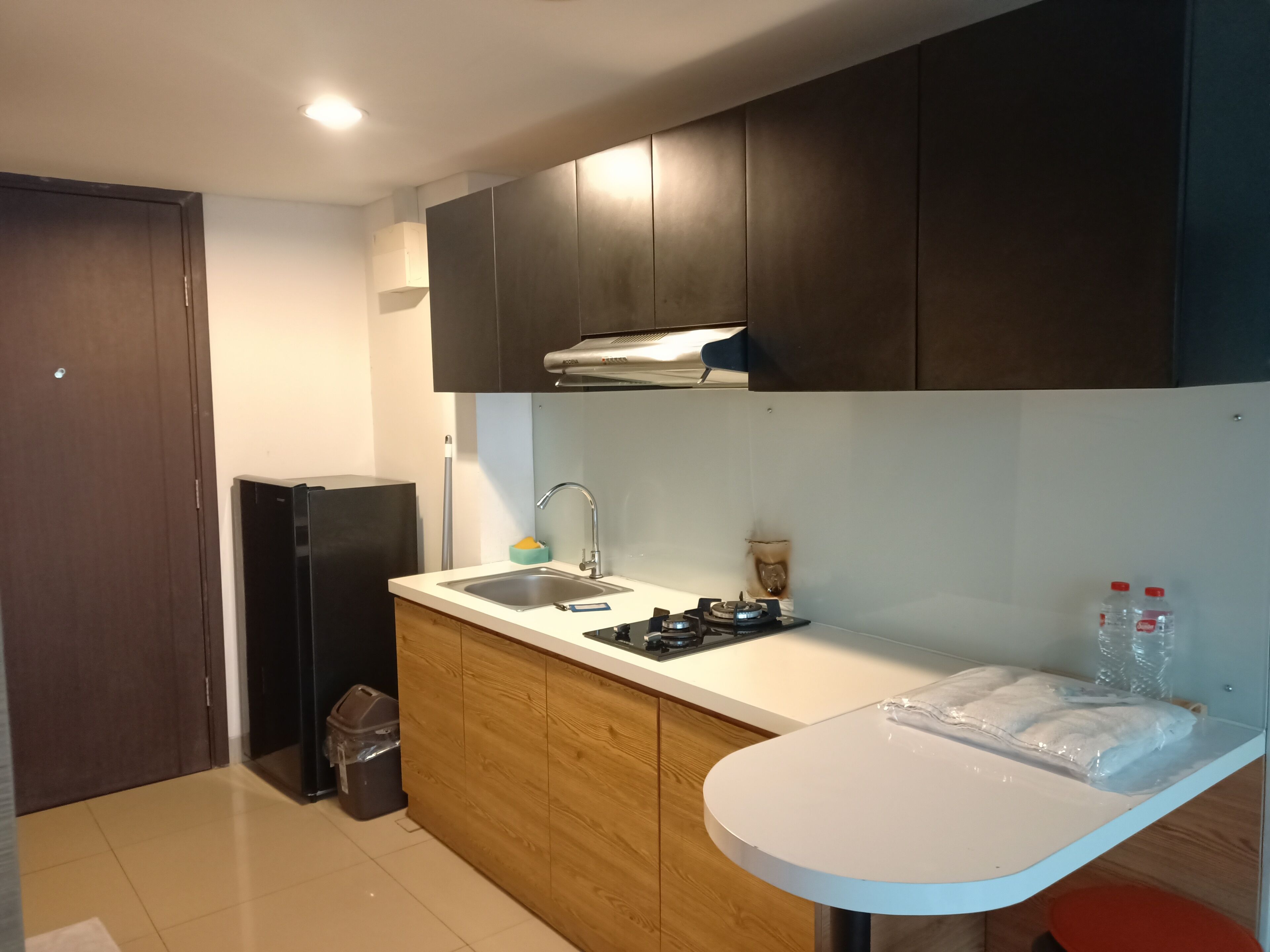 A modern kitchen with dark wooden cabinets, a white countertop, a stainless steel sink, and a gas stove.