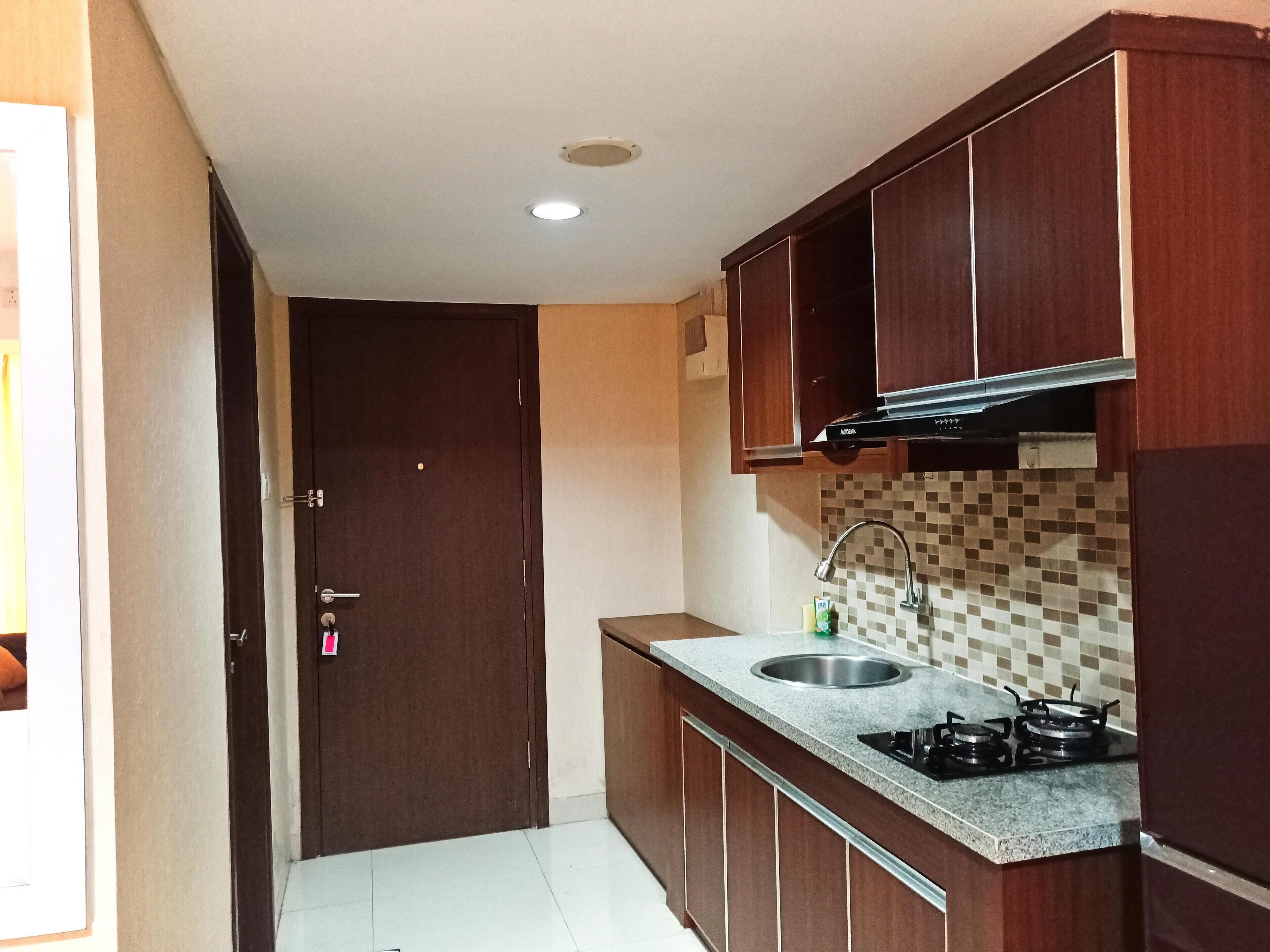 A compact kitchen with wooden cabinets, a stainless steel sink, and a gas stove.