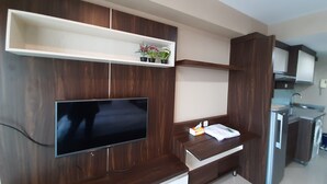 Una cocina moderna con armarios de madera integrados, un televisor de pantalla plana y una pequeña encimera con un lavamanos y un refrigerador.