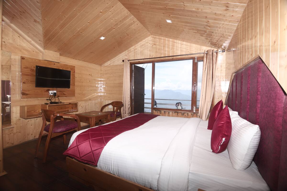 Una habitación de cabaña de madera con una cama, un escritorio, una silla y un televisor montado en la pared.