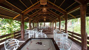 An indoor recreational area with a foosball table, white plastic chairs, and a wooden deck.