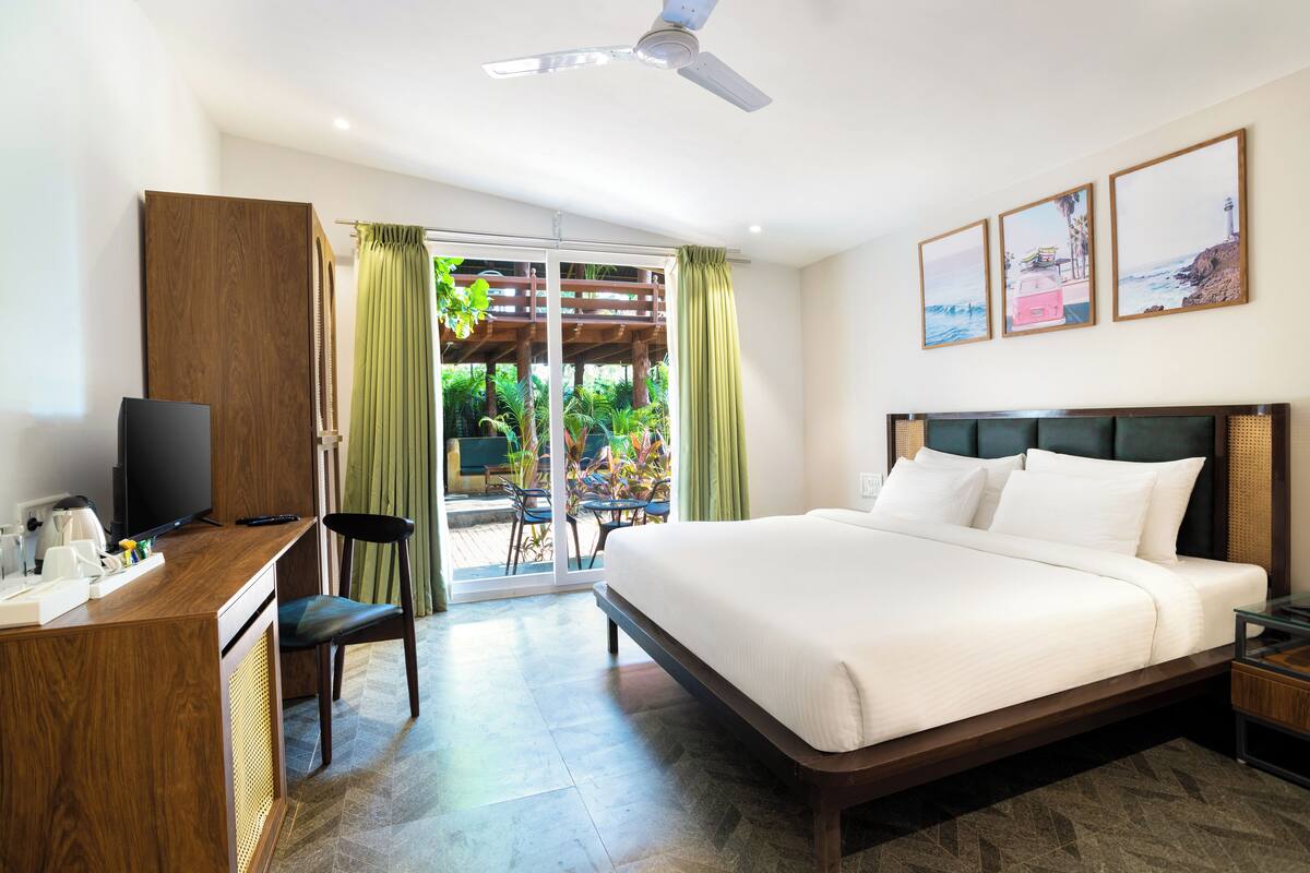 Habitación de hotel con cama, escritorio, televisor y vistas al exterior.