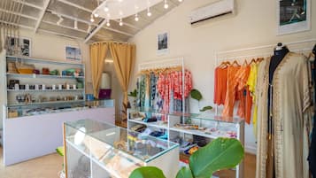Une boutique avec des vitrines en verre, des portants à vêtements et une plante au premier plan.